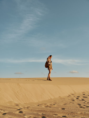 Lonely traveler trekking through the vast desert landscape under the scorching sun, carrying a backpackの写真素材