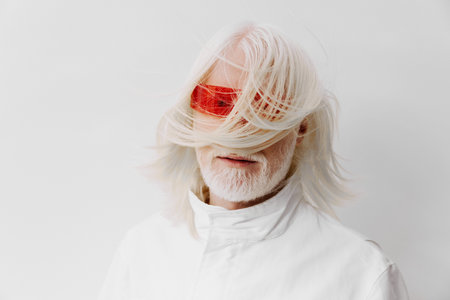 Elderly man with long white hair and stylish red sunglasses against a minimalistic white background, embodying a modern and avant garde lifestyle conceptの写真素材