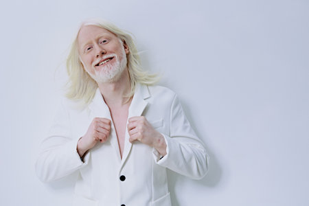 Smiling man in a white suit against a minimalistic white background, exuding confidence and...