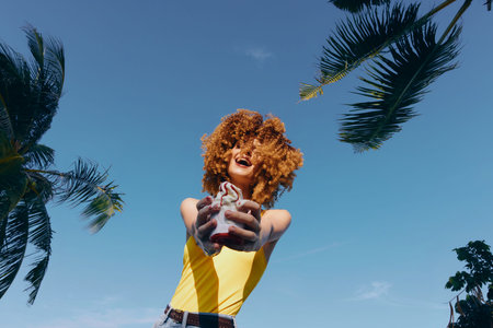 Happy woman holding a drink under a blue sky with palm trees in the background