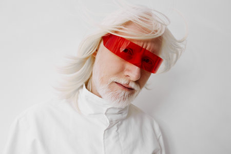 Futuristic portrait of a man with long white hair and red sunglasses, set against a minimalistic white background, conveying a sense of innovation and modernity with a stylish appearanceの写真素材