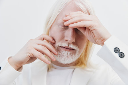 Portrait of a thoughtful elderly man with long white hair in a white suit, expressing deep emotions...