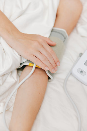 Person lying in bed with blood pressure cuff on arm and heart rate monitor on nearby table