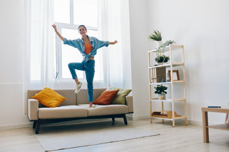 Jumping for Joy: A Carefree Woman Dancing to Music in her Happy Homeの写真素材