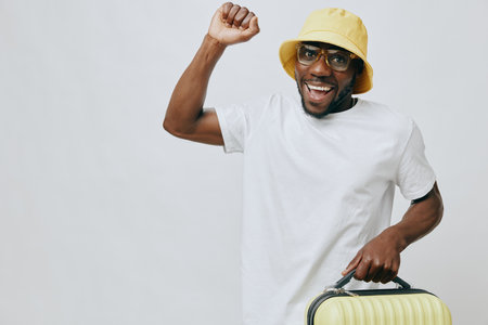 Happy man celebrating success with a yellow bucket hat and glasses, casual outfit, holding a stylish...