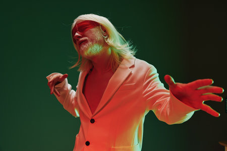 Stylish man performing in a vibrant atmosphere with a striking blend of green and red colors,...