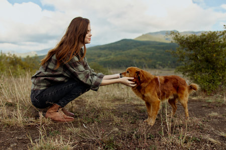 Woman bonding with a dog in a picturesque mountain field during travel and outdoor adventure therapy sessionの写真素材