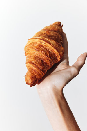 Person holding a croissant on a white background croissant is in the persons handの写真素材