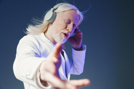 elderly man enjoying music, relaxed and engaged, wearing headphones, light gray background, expressing joy and passion for sound, peaceful ambiance of listening pleasureの写真素材