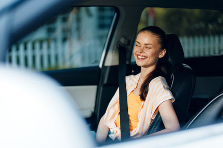 happy girl in car, smiling, sitting comfortably, bright casual attire, warm sunlight, relaxed expression, driving experience, joyful moments, interior car scene, summer vibesの写真素材