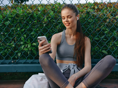 Young woman in sportswear enjoying music on her smartphone outdoorsの写真素材