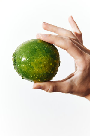 Person holding up a green fruit on a white backgroundの写真素材