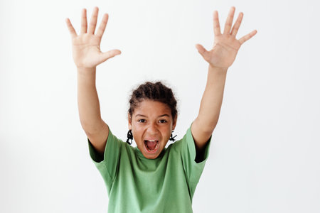 Young boy with hands up in trendy pose against white backgroundの写真素材