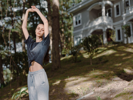 Young woman stretching outdoors in casual sportswear, enjoying fresh air and nature in a serene environment, promoting fitness and well being conceptsの写真素材
