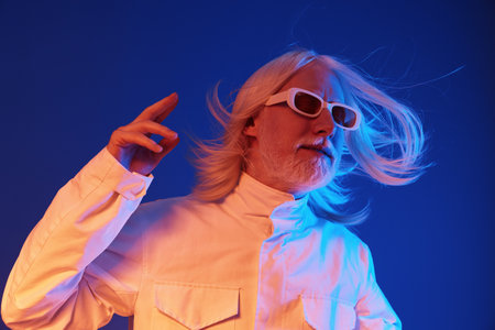 Futuristic man in white jacket with long hair against a blue background, striking a confident pose while wearing stylish sunglasses, embodying a modern and artistic vibeの写真素材