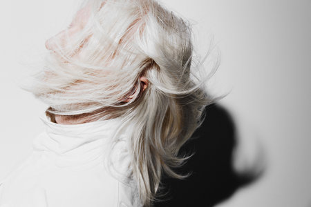 Hair movement, white background, creative photography, dynamic portrait of a person with long white hair in motion Sleek and modern style conveying freedom and eleganceの写真素材
