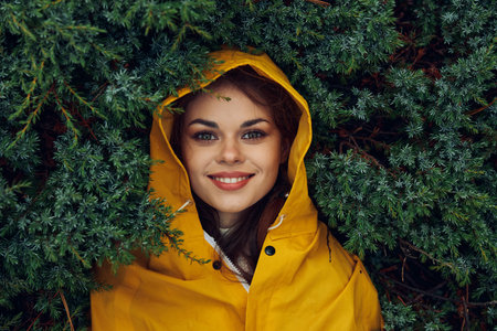 Solo Traveler Embracing Nature Young Woman in Yellow Raincoat Surrounded by Trees in Forest Wonderlandの写真素材