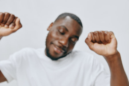 joyful man dancing, happiness, celebration, music enjoyment, casual white t shirt, studio background, positive emotions, energetic movement, focus on expression, vibrant atmosphereの写真素材
