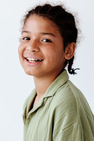 Stylish young boy in green shirt exudes confidence against clean white backgroundの写真素材
