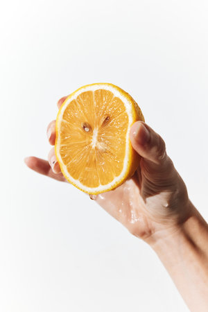 Person holding a slice of orange with a drop of water on itの写真素材