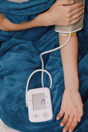 Person laying in bed with a blood pressure monitor on one arm and a cuff on the other armの写真素材