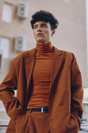 Stylish man in a brown suit and turtleneck, posing confidently outdoors Urban backdrop with a modern architectural vibeの写真素材