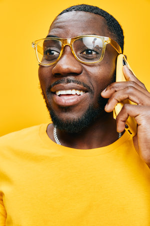 Happy man talking on a yellow phone, wearing yellow glasses and a yellow shirt, expressive smile,...