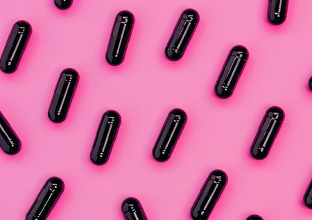 Black capsules on a vibrant pink background, creating a striking contrast The capsules are arranged in a regular pattern, emphasizing their glossy finish and unique shapeの素材