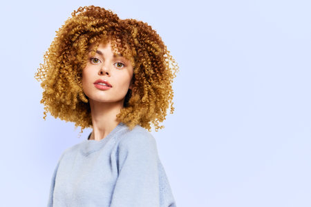 Portrait of a young woman with curly hair against a light blue background, exuding confidence and...