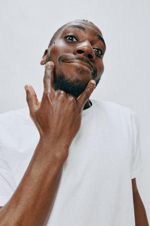 Happy man making a playful gesture wearing a white t shirt, with a light grey background, expressing joy and confidence, showcasing a vibrant personalityの写真素材