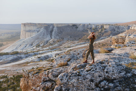 Woman standing on cliff edge with arms outstretched in front of her embracing the beauty and freedom of travelの写真素材