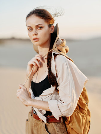 Lonely female traveler with backpack in scenic desert landscape with sand dunes in the backgroundの写真素材