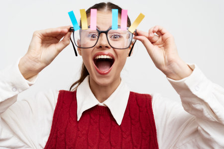 Cheerful woman with colorful clips on glasses, bright expression, white background, vibrant and playful concept of creativity and funの写真素材