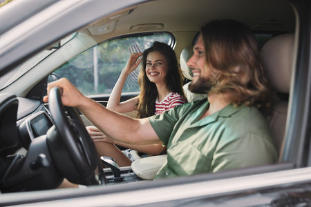 Happy couple driving in a car, enjoying their time together with joyful expressions Bright sunlight filters through the windowsの写真素材