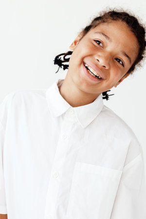 Happy young boy with a bright smile in a white shirt against a clean white backgroundの写真素材