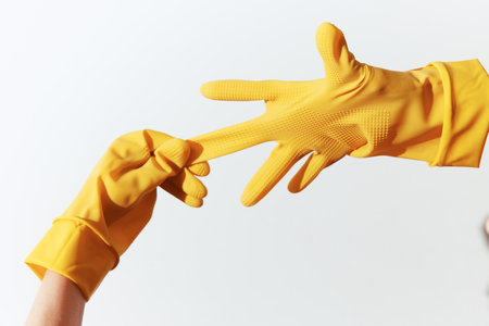 Two people in yellow rubber gloves reaching out to each other on a white backgroundの写真素材