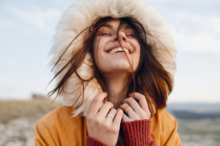 Fashionable woman smiling in fur coat and holding hands to face in joyful expressionの写真素材