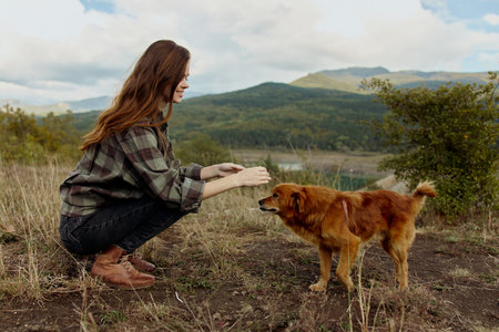 Woman petting dog in scenic mountain meadow, peaceful travel moment with nature beauty and companionshipの写真素材