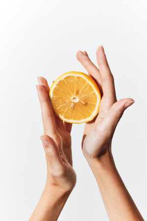 Hands holding an orange slice against a white backgroundの写真素材