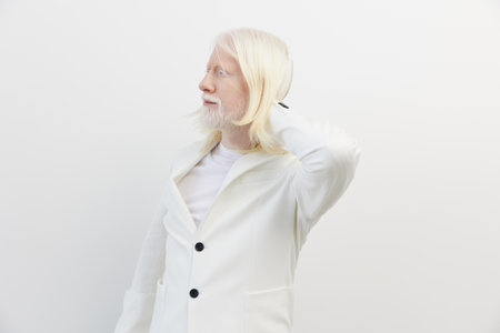 Portrait of a person with long white hair wearing a stylish white blazer, set against a minimalistic white background, conveying a sense of elegance and modernityの写真素材