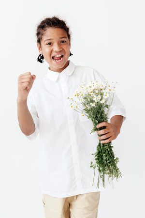 Young boy in white shirt holding a bouquet of chamomile flowers in a summer settingの写真素材