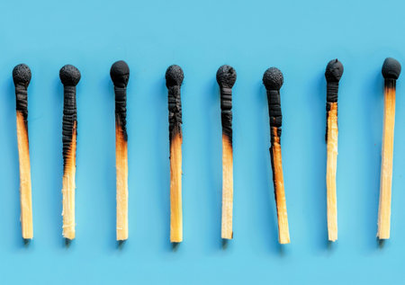 Burnt matches on a blue background, showcasing the contrast between untouched and charred tips, representing the theme of loss and transformation Ideal for creative projectsの素材