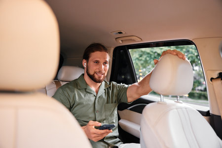 Young man using smartphone in the back seat of a modern car