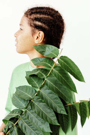 Young woman with leafy plant covering her face in minimalist white background