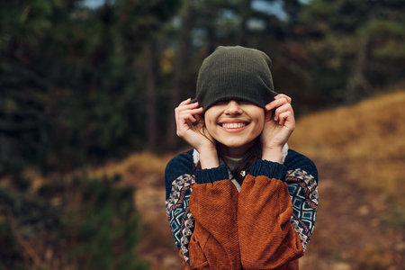 A woman enjoying a peaceful moment surrounded by nature, wearing a stylish beanie and showcasing inner beautyの写真素材