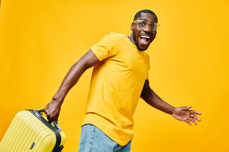 cheerful traveler, happy man with suitcase, smiling, yellow background, casual outfit, excitement, summer vacation, adventure spirit, vibrant emotions, anticipationの写真素材
