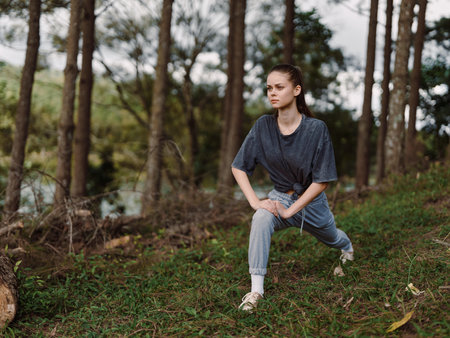 Focused young woman stretching in a forest, preparing for outdoor workout Fitness and wellness...
