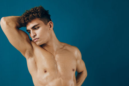Thoughtful young man posing against a blue background, showcasing confidence and self-expression. Emotional portrait reflecting male beauty and strength.の写真素材