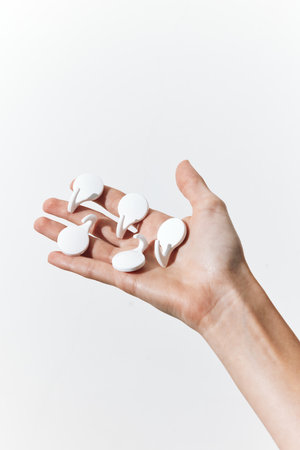 Hand holding a bunch of white toothpicks in front of a white background, with a copy of the...