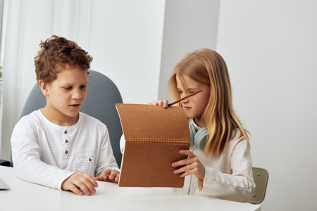 Happy Caucasian Boy and Girl Studying with Laptops at Home, Engrossed in Online Educationの写真素材
